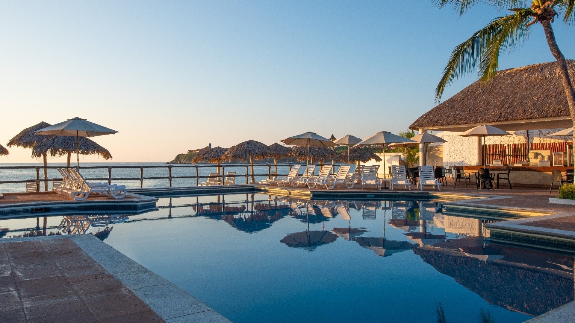 a large swimming pool with chairs and umbrellas around it