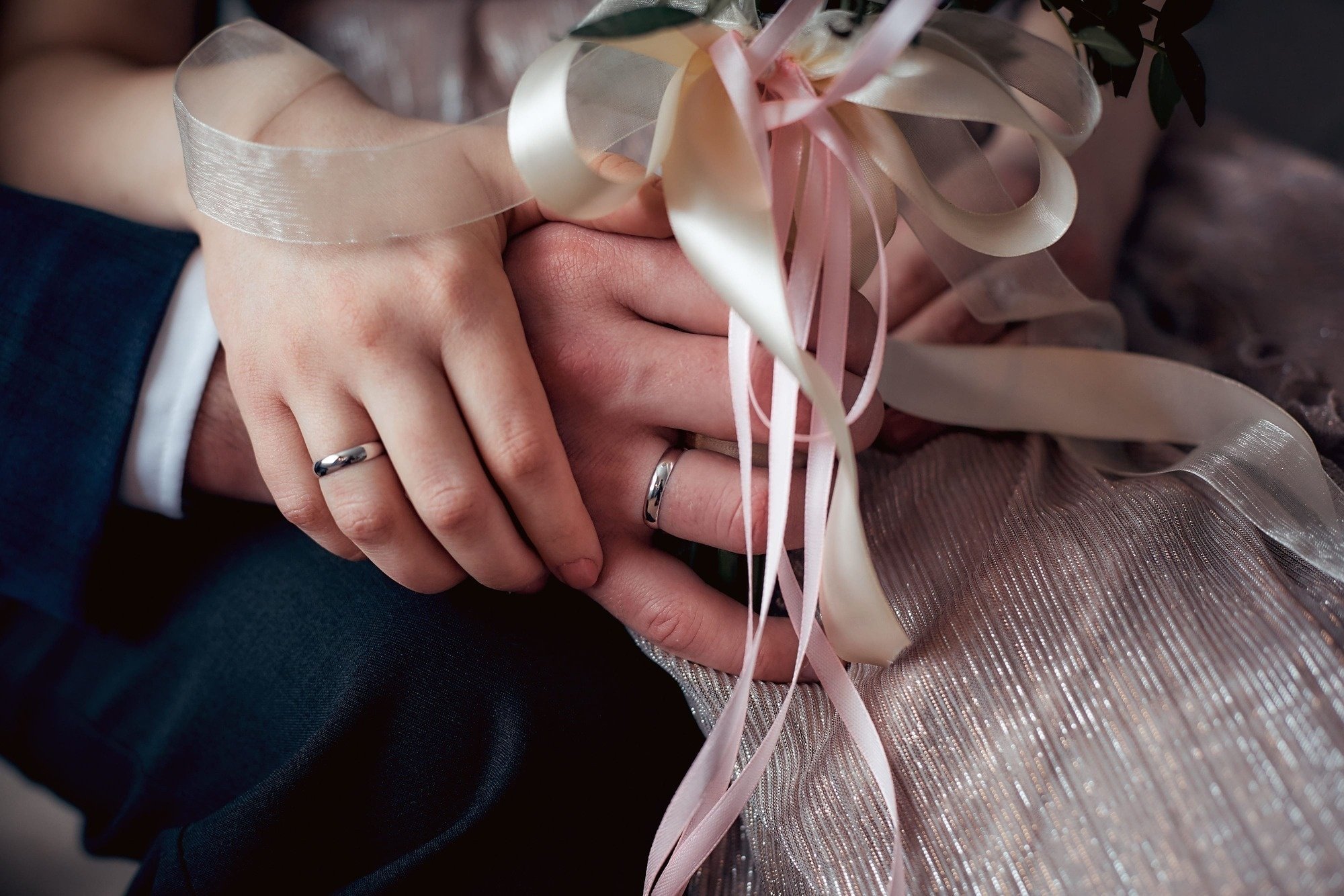 a bride and groom hold hands with their wedding rings on