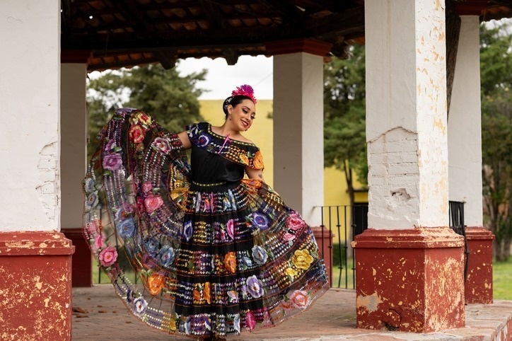 Una mujer en un traje de danza oriental con un gorro de papá noel en el  fondo de palmeras en el puente.