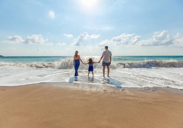 a family is standing on a beach holding hands .