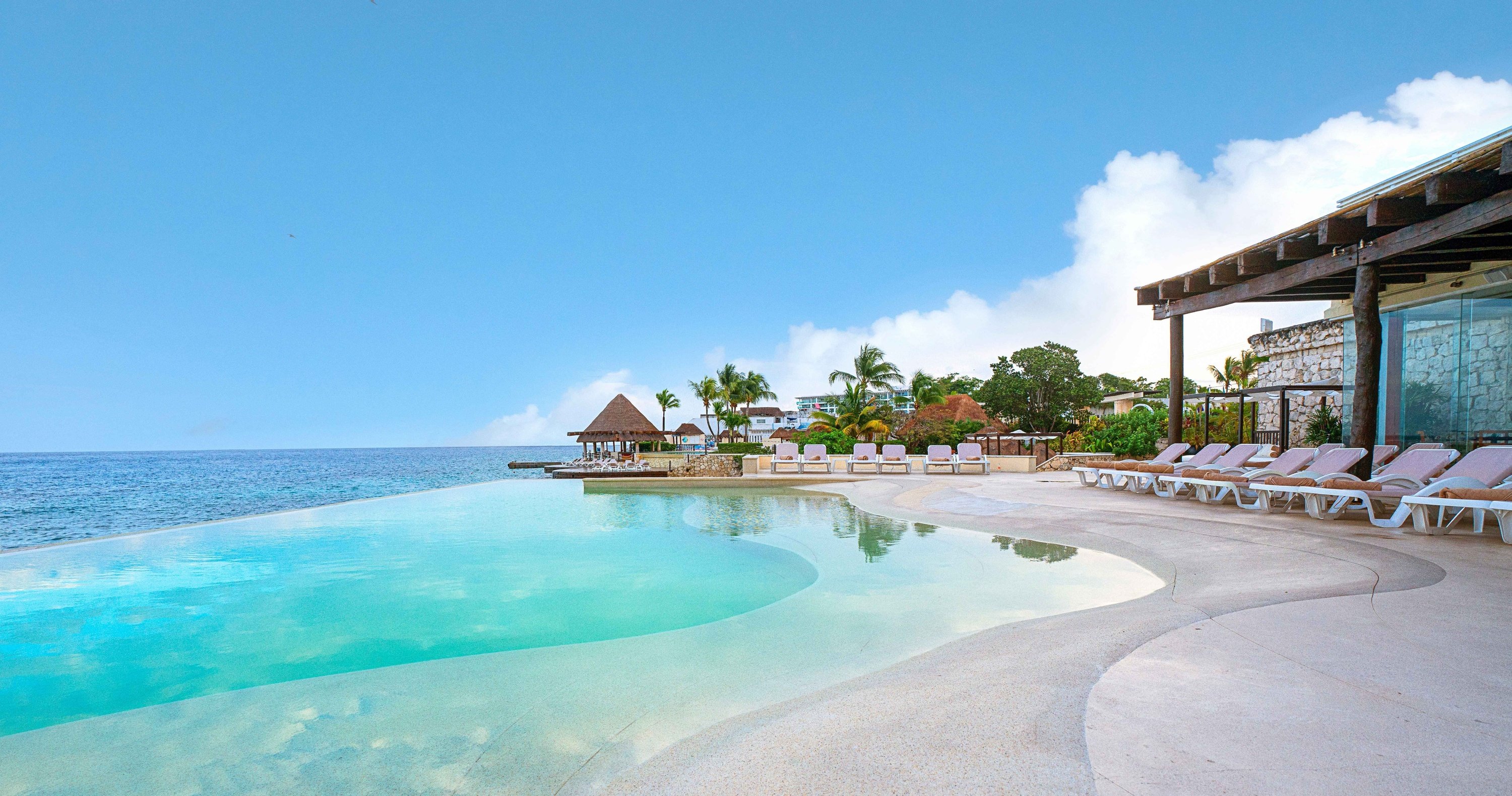 Pareja en hamaca cerca de piscina infinity con vistas al mar en el Hotel Grand Park Royal Cozumel