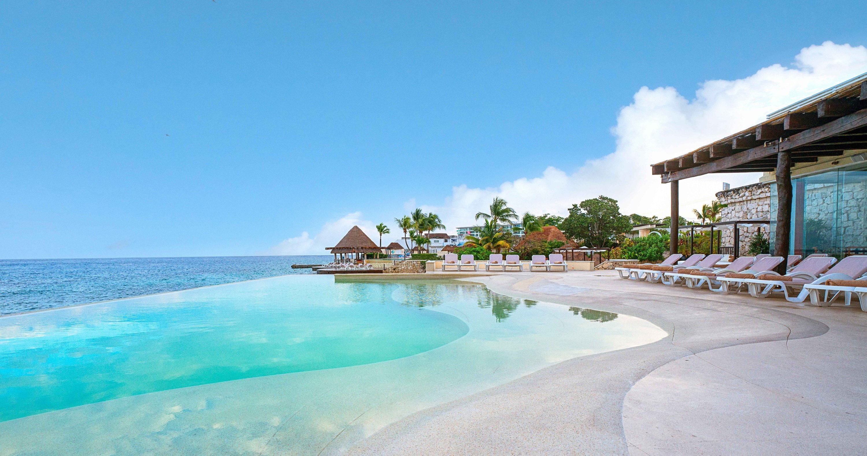 Pareja en hamaca cerca de piscina infinity con vistas al mar en el Hotel Grand Park Royal Cozumel