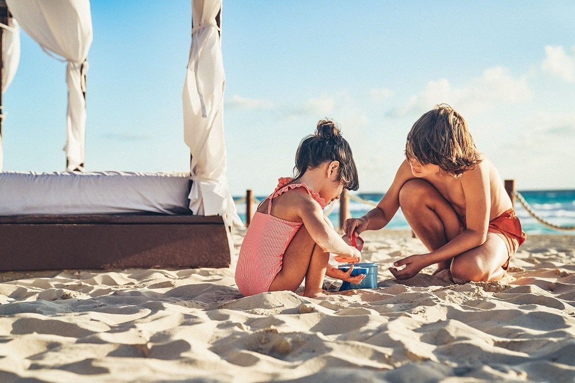 a boy and a girl are playing in the sand on the beach
