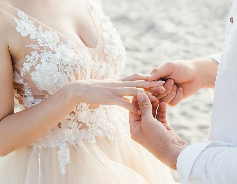 Novio poniendo anillo en mano de novia en la playa,  Park Love organiza tu luna de miel 