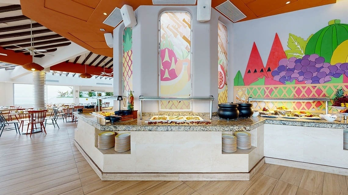 Área de restaurante espaciosa con mesas, sillas y buffet del Hotel Grand Park Royal Puerto Vallarta