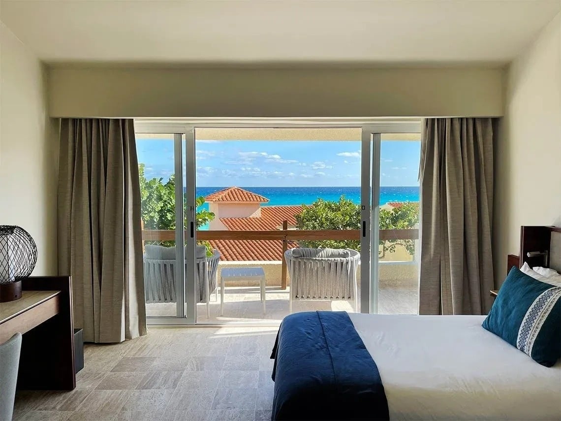 um quarto com uma cama e uma varanda com vista para o oceano