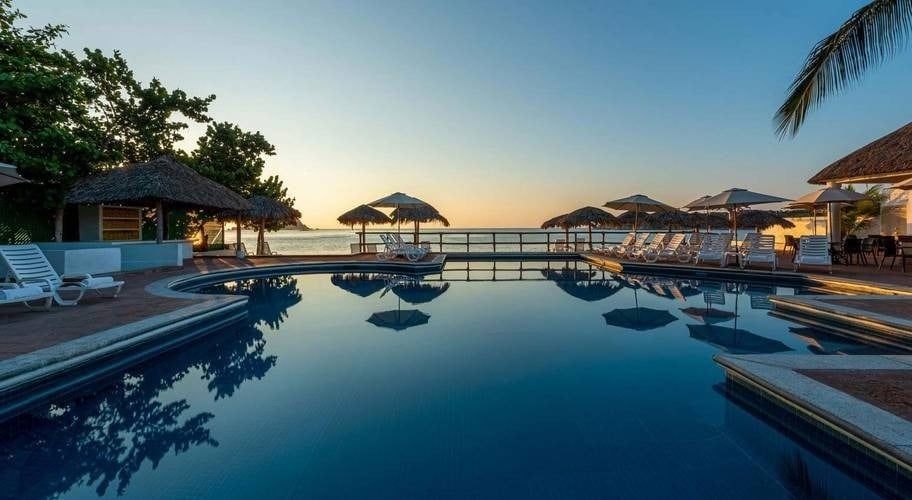 Pôr do sol sobre a piscina e bar com vista para o mar no Hotel Park Royal Beach Huatulco