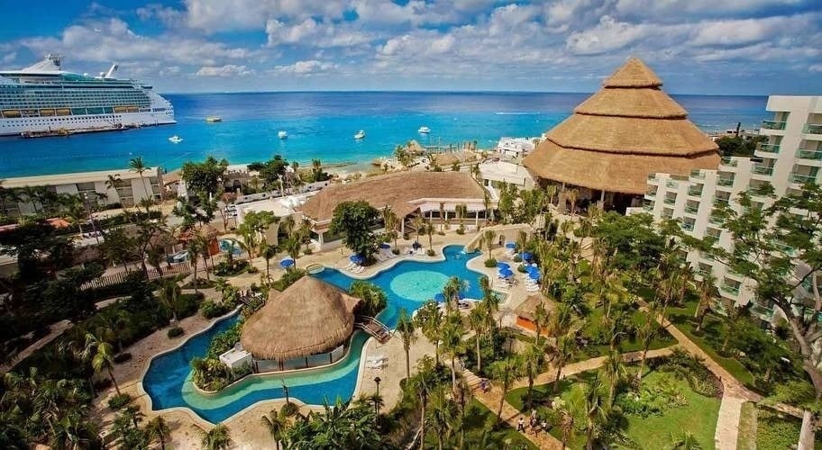 an aerial view of a resort with a cruise ship in the background