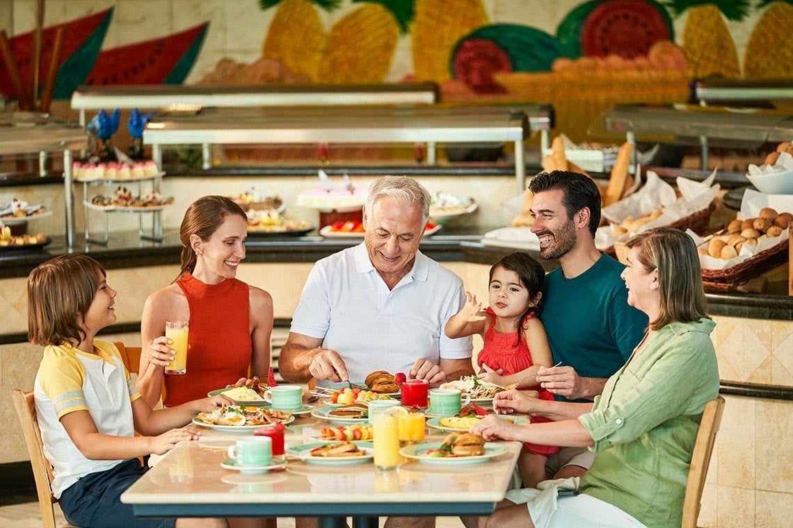 a family is sitting at a table eating food