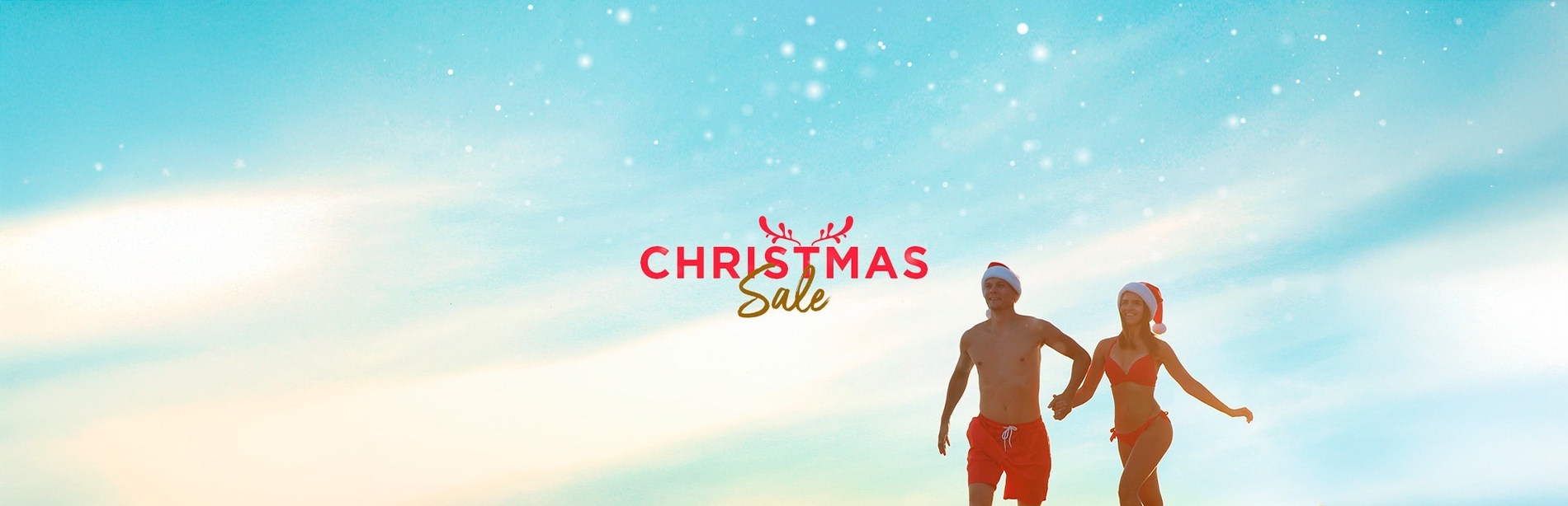 duas mulheres sentadas na praia com chapéus de papai noel