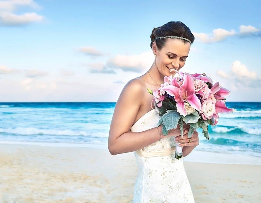 Noiva com buquê de flores na praia. Celebre o seu casamento no Hotel Grand Park Royal Cozumel