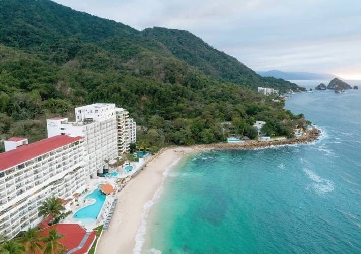 an aerial view of a beach resort with mountains in the background .