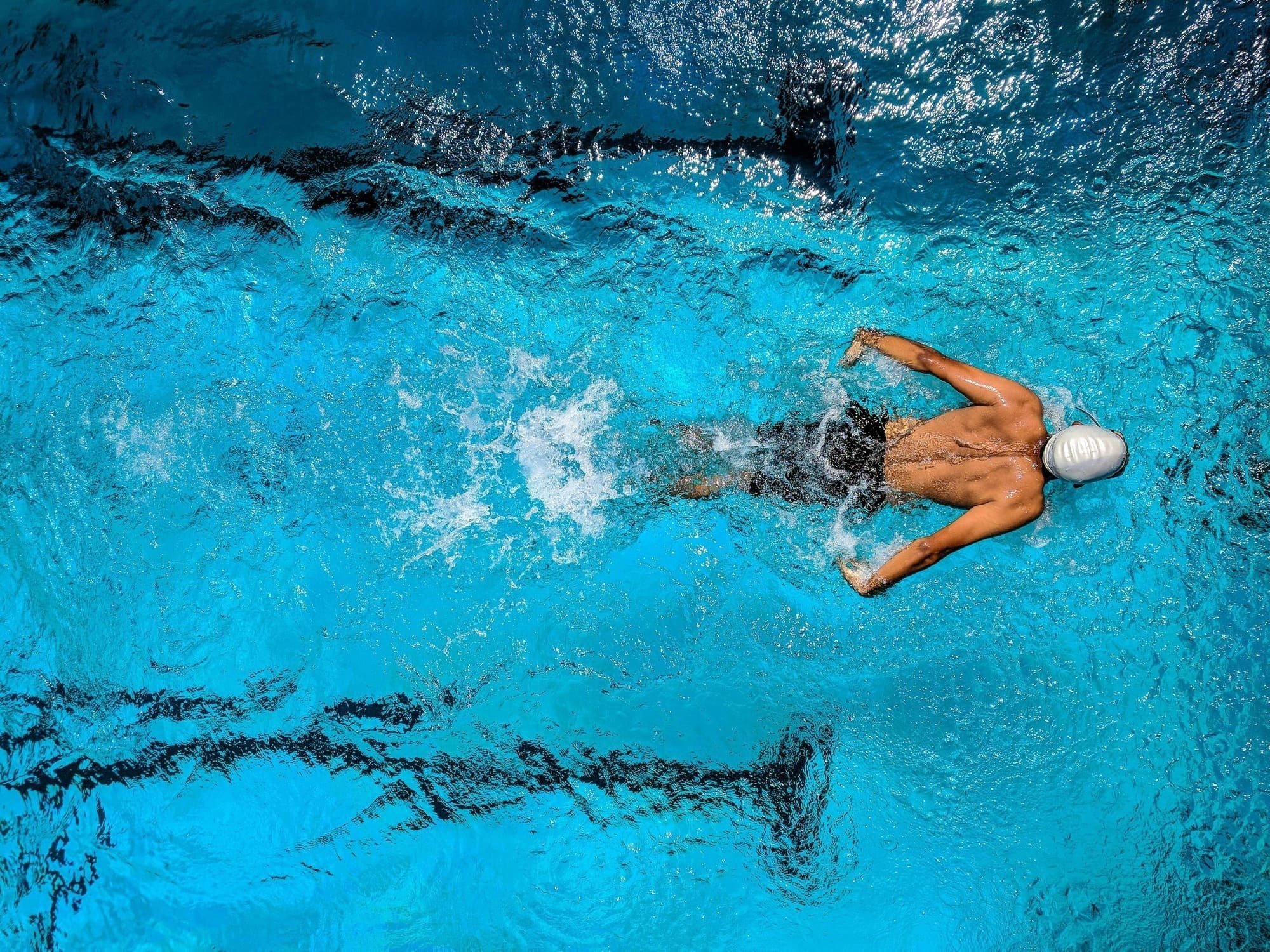 um homem está nadando em uma piscina com água azul