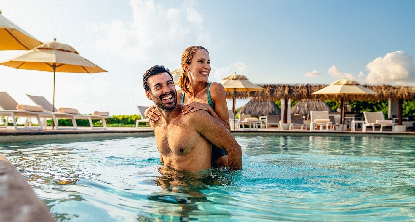 Pareja sonriente disfruta piscina en Hotel Park Royal Beach Cancún, Caribe Mexicano