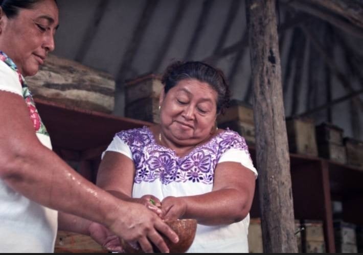 a woman in a purple top is holding a bowl