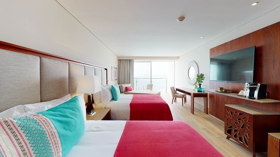 Habitación con dos camas, un sofá cama y vistas al mar del Hotel Grand Park Royal Puerto Vallarta