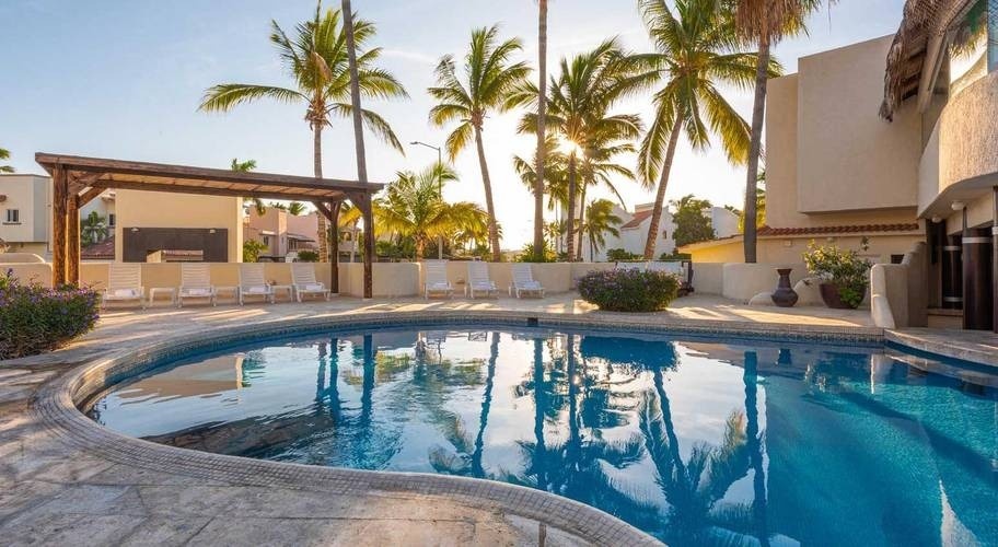 Vista panorâmica da piscina externa com redes e palmeiras no Homestay Los Cabos