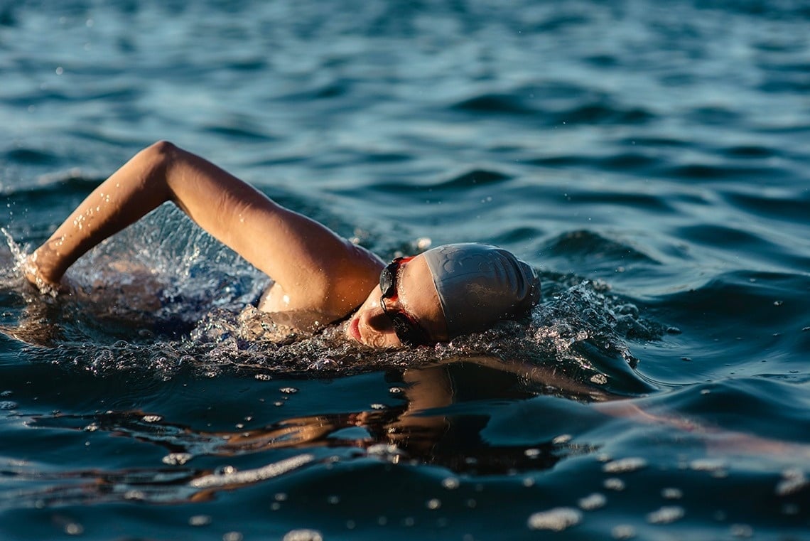 a woman wearing a swim cap is swimming in the ocean
