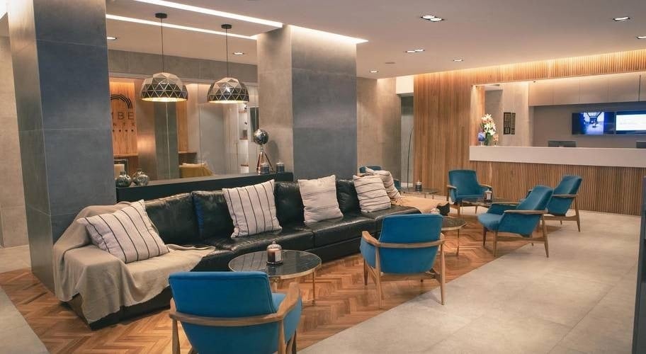 Zona de conforto com sofás e mesas na recepção do hotel City Buenos Aires