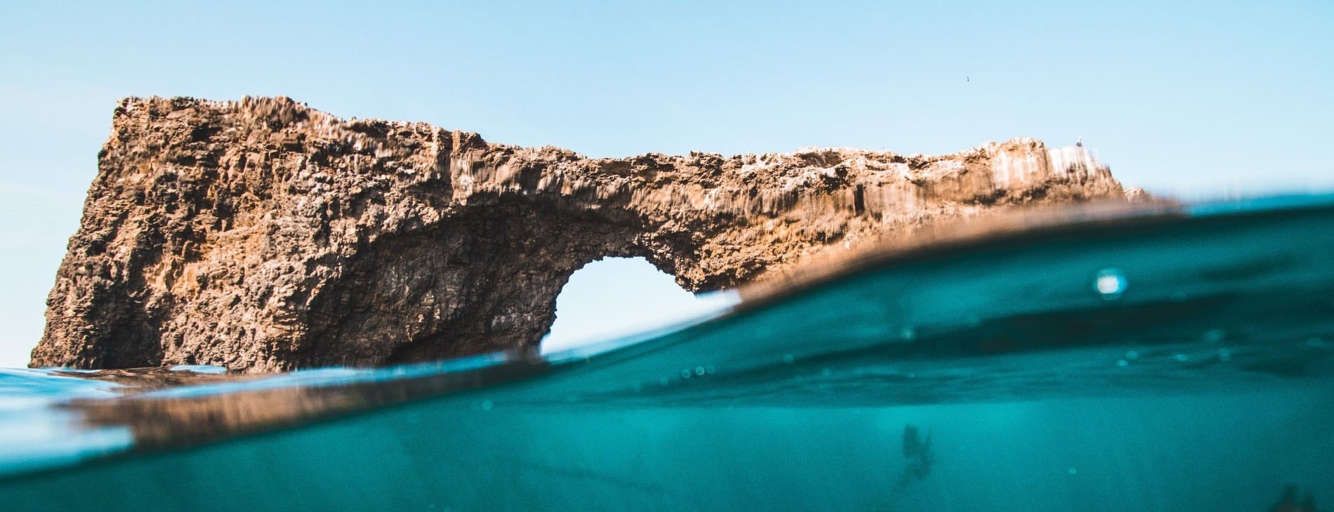 uma rocha com um arco na água