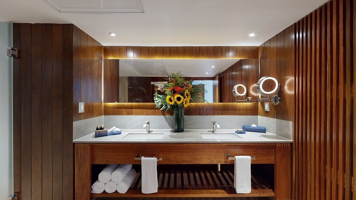 Banheiro aconchegante com espelho iluminado e vaso de flores no Hotel Grand Park Royal Puerto Vallarta