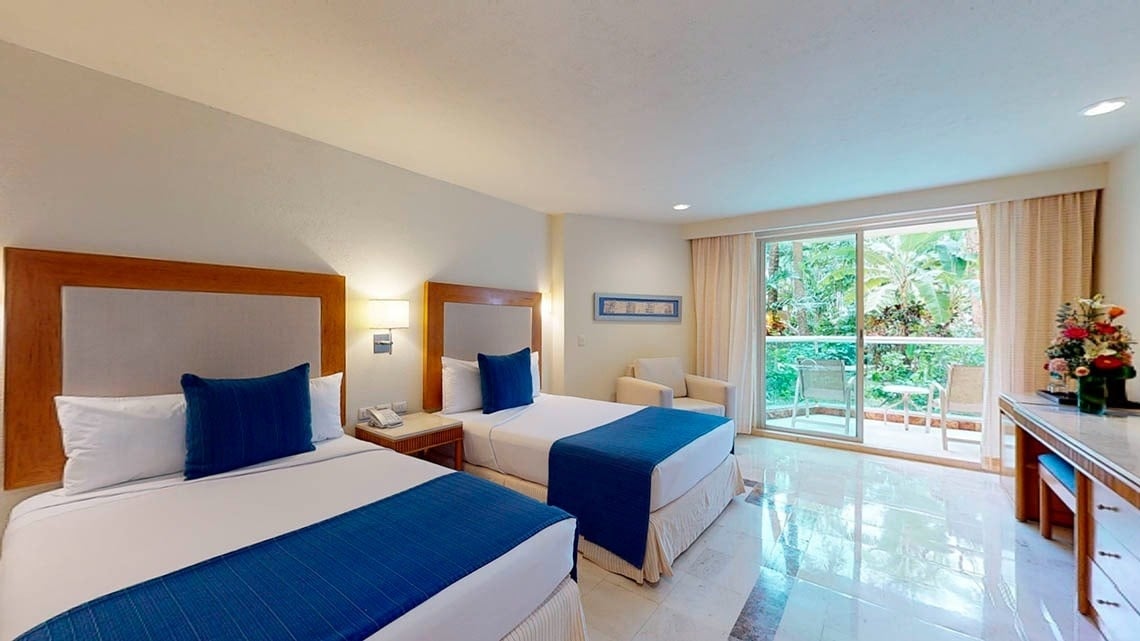 Quarto com duas camas e terraço com vista para um jardim do Hotel Grand Park Royal Cozumel