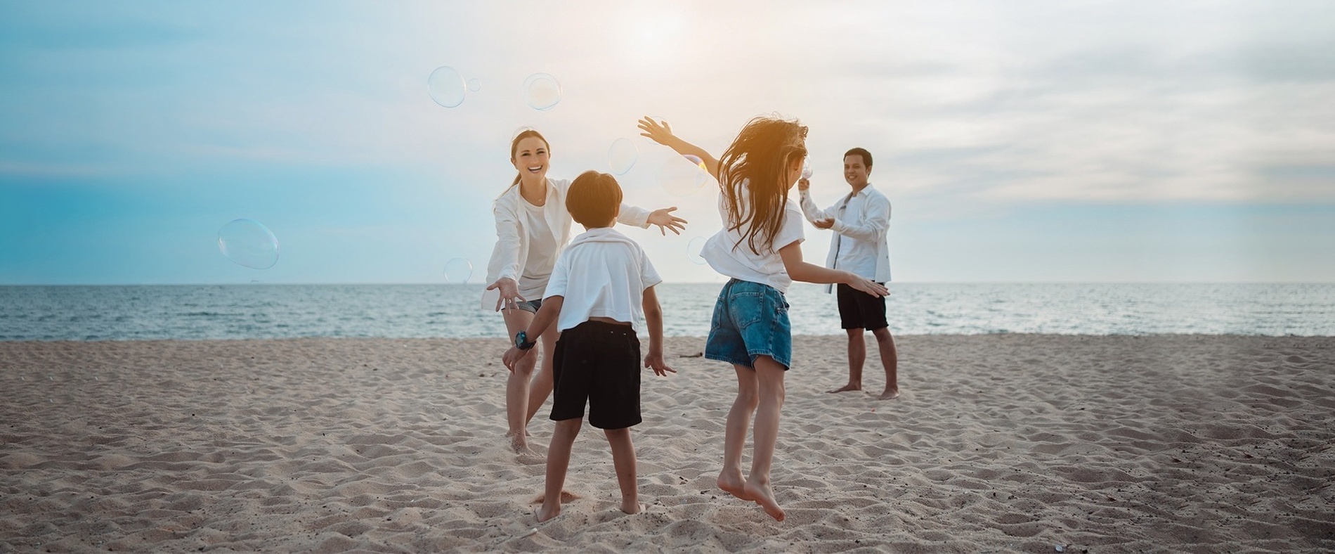 una familia juega con burbujas de jabón en la playa