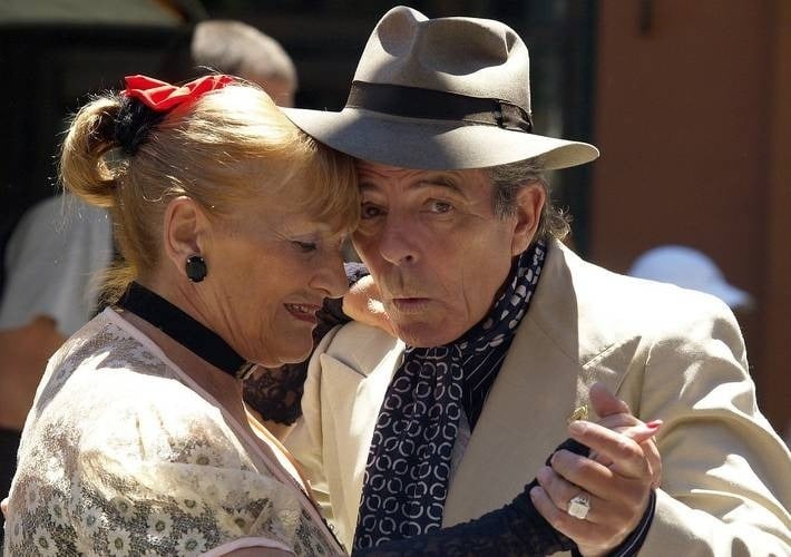 a man and woman are dancing together and the man is wearing a hat