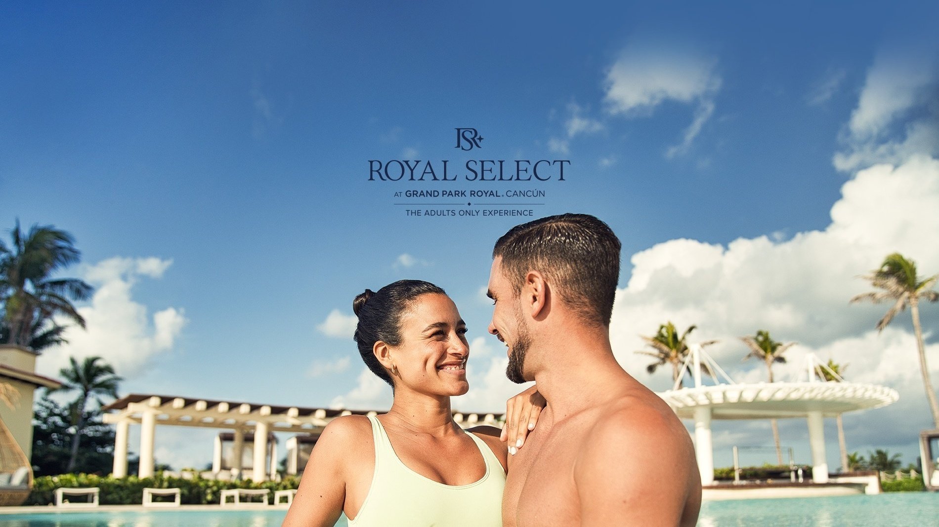 a man and a woman are looking at each other in front of a pool at royal select at grand park royal cancun