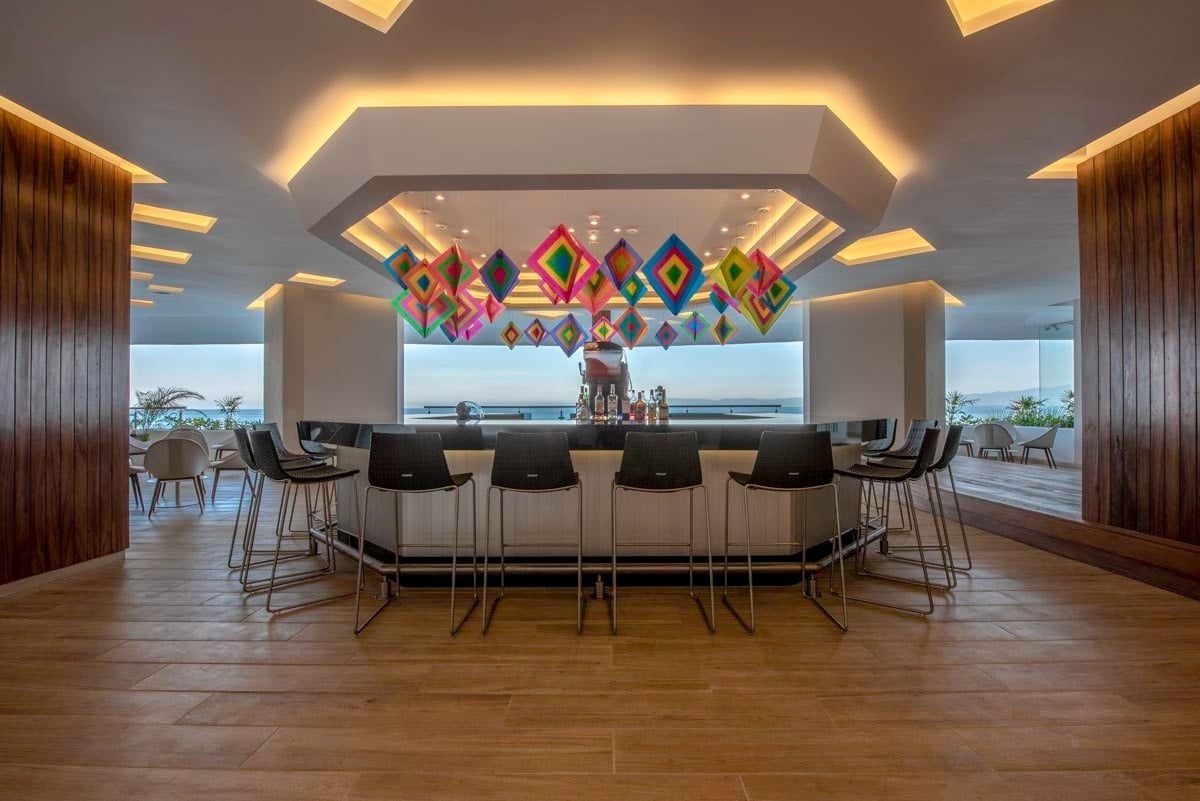 a restaurant with a bar and stools and a view of the ocean