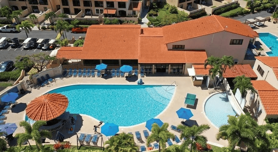 an aerial view of a large swimming pool surrounded by chairs and umbrellas