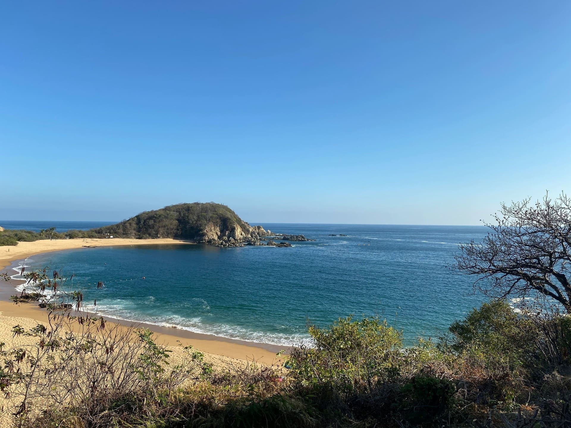 uma praia com uma pequena ilha ao fundo