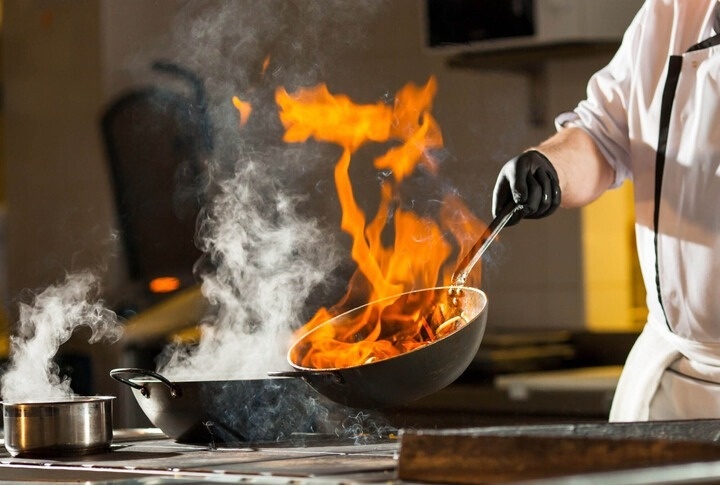 um chef está cozinhando com fogo em uma panela