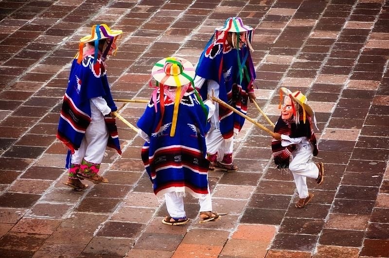 a group of people dressed in colorful costumes are walking on a brick sidewalk