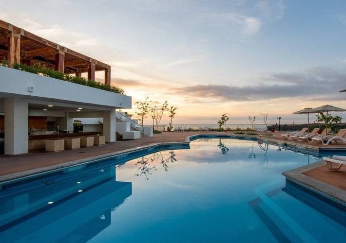 a large swimming pool with a bar and chairs around it