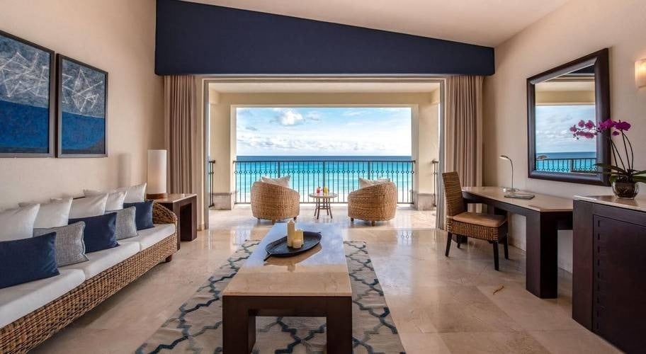 Sofás, mesa, escritorio y terraza con vistas al mar Caribe del Hotel Grand Park Royal Cancún