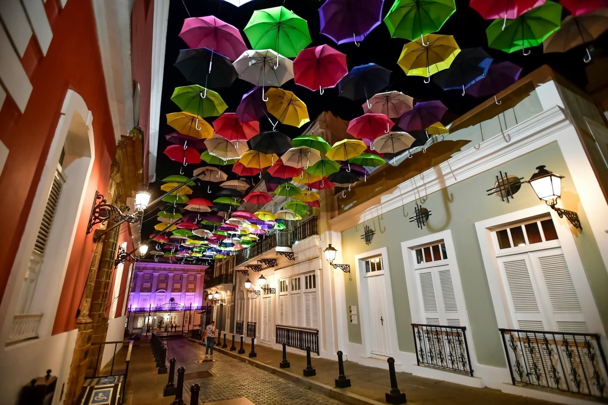 a row of colorful umbrellas hang from the ceiling of a street