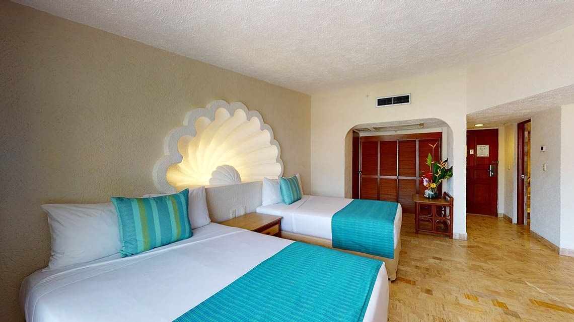 Vista lateral do quarto Deluxe Pool View, com camas, guarda-roupa e cômoda no Park Royal Beach Acapulco Hotel