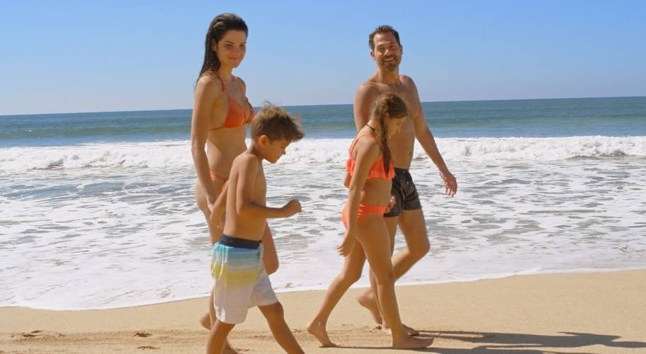 Familia cogidos de la mano paseando en la playa