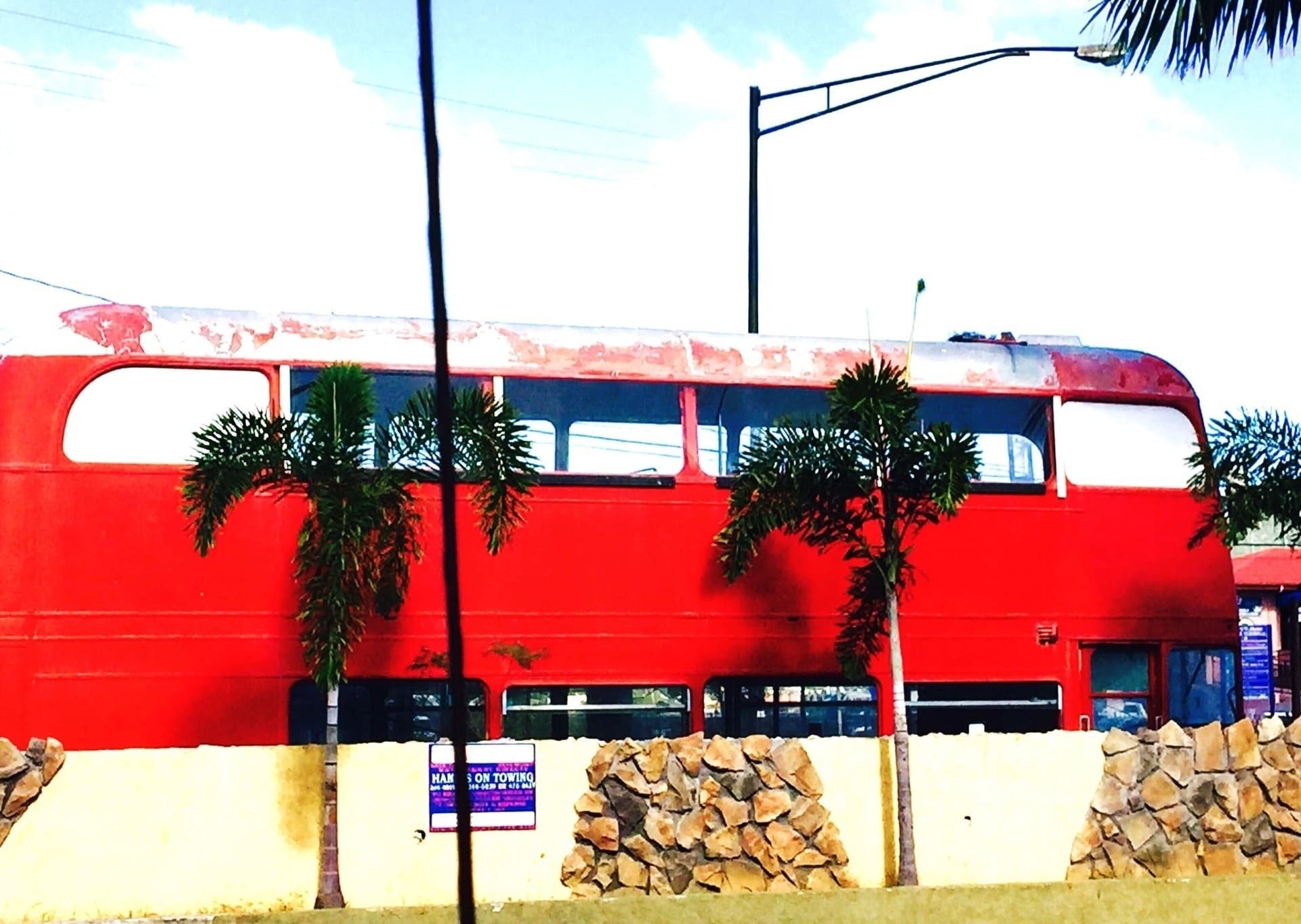 a red double decker bus is parked in front of a stone wall