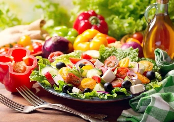 a salad with tomatoes , cucumbers , olives , feta cheese and peppers on a plate with a fork .