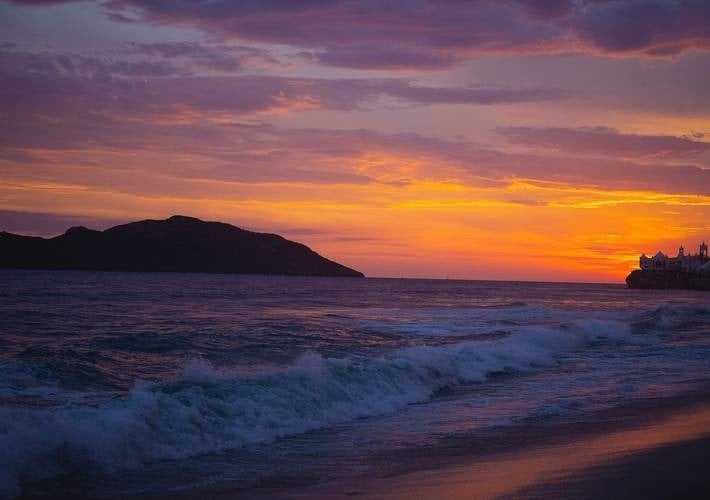 um pôr do sol roxo e laranja sobre o oceano