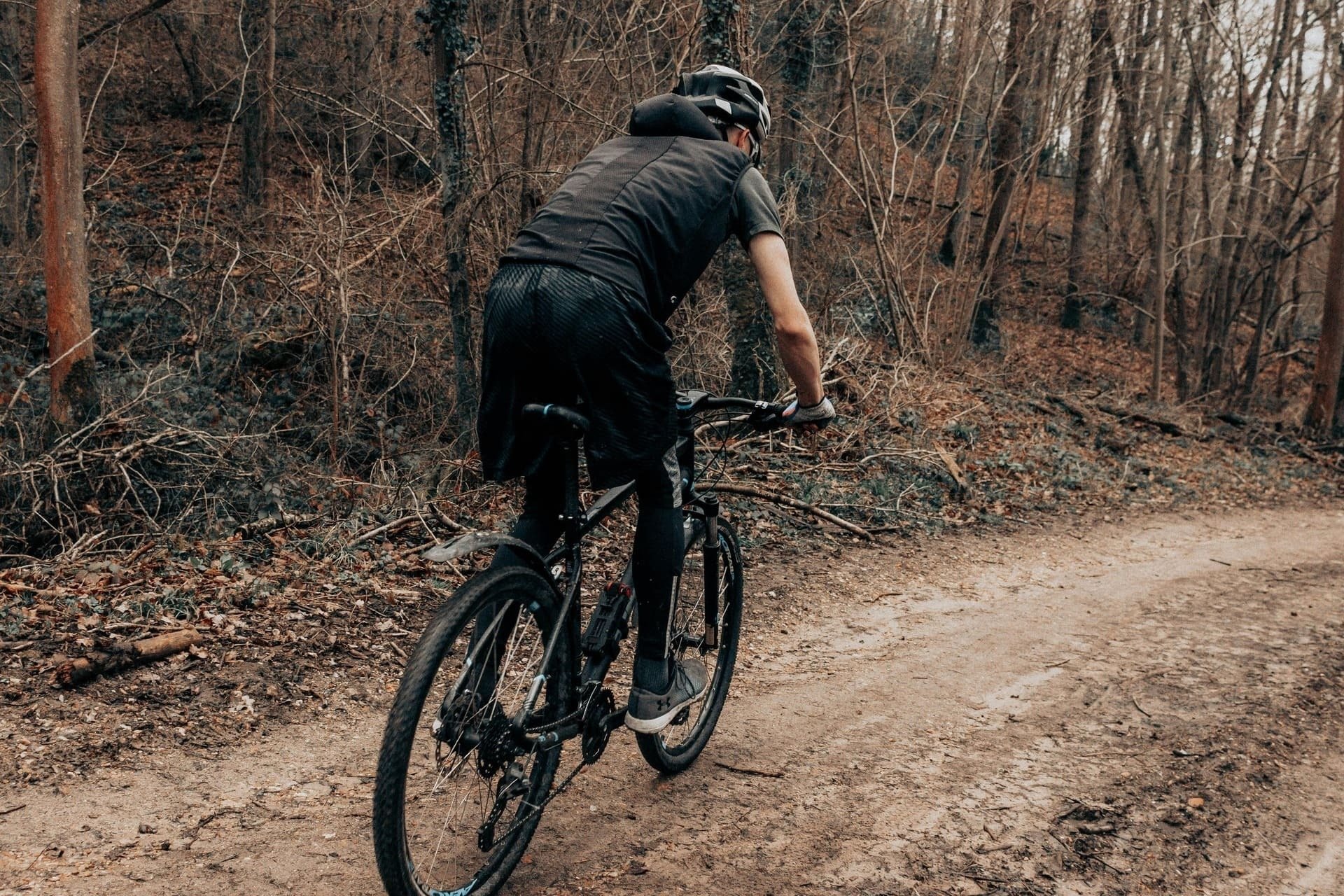 un hombre monta una bicicleta por un camino de tierra en el bosque