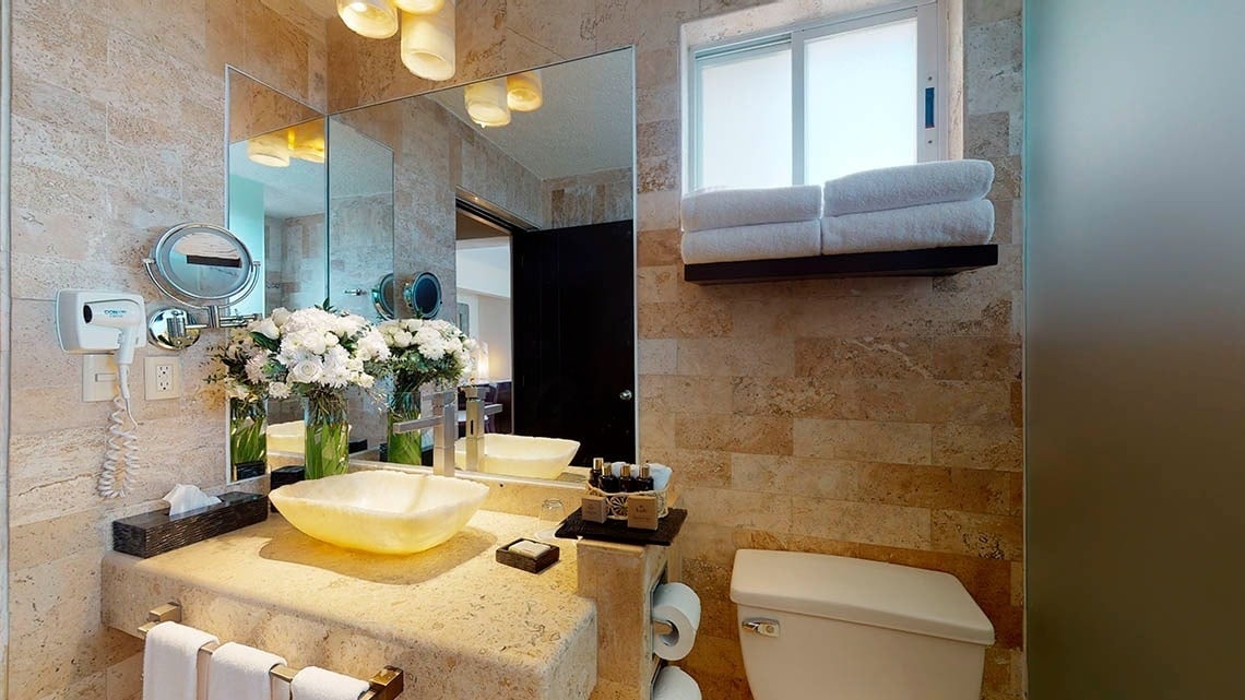 Detalle del lavabo con espejo, secador y jarrón de flores del Hotel Grand Park Royal Cancún