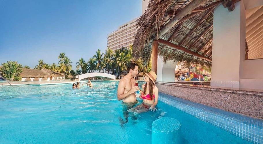 Couple enjoying a cocktail in the pool of the Beach Ixtapa resort in Mexico