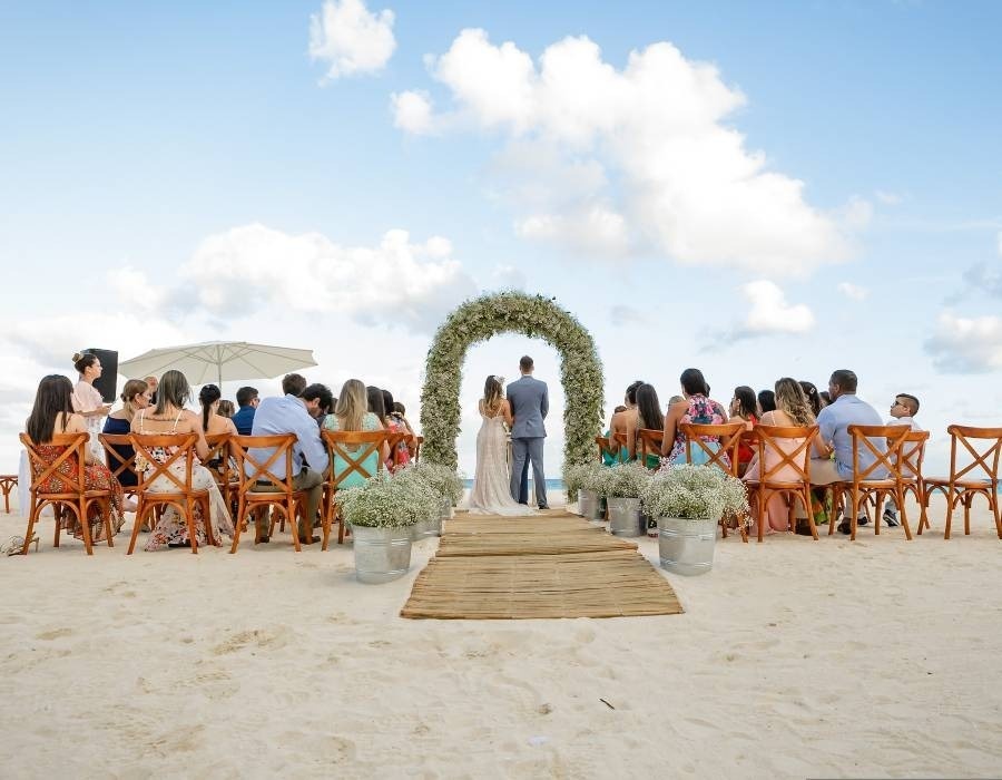 Casal de noivos em altura, com convidados sentados em cadeiras na praia, Park Love by Park Royal hotéis e resorts