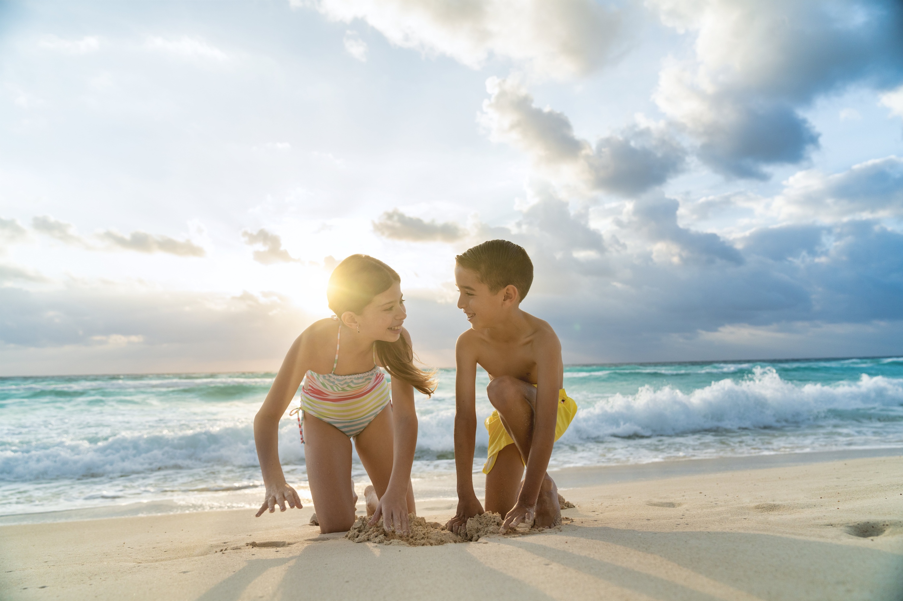 a boy and a girl are playing in the sand on the beach