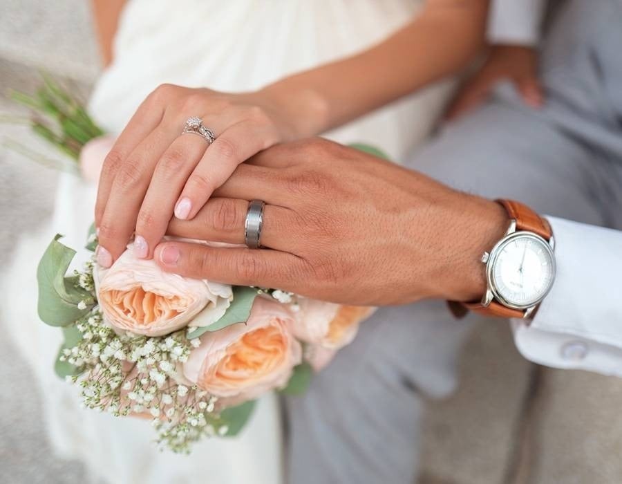 Manos de recién casados mostrando sus anillos y el ramo de flores en el Hotel Park Royal Beach Huatulco
