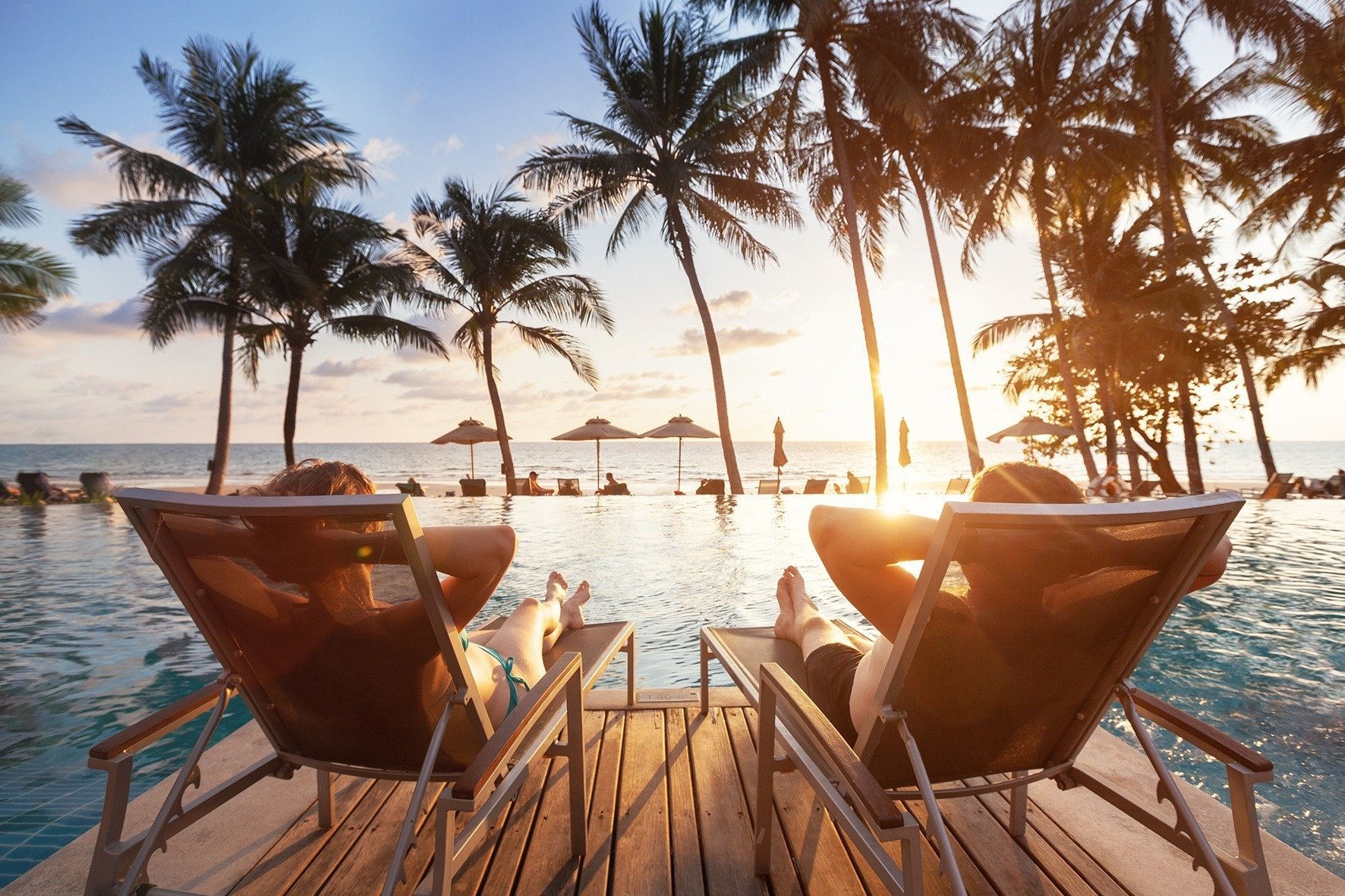 a couple sits in lawn chairs near a swimming pool