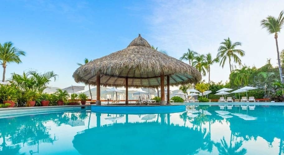 Bar com telhado de palmeira ao lado da piscina externa do Park Royal Beach Acapulco Hotel